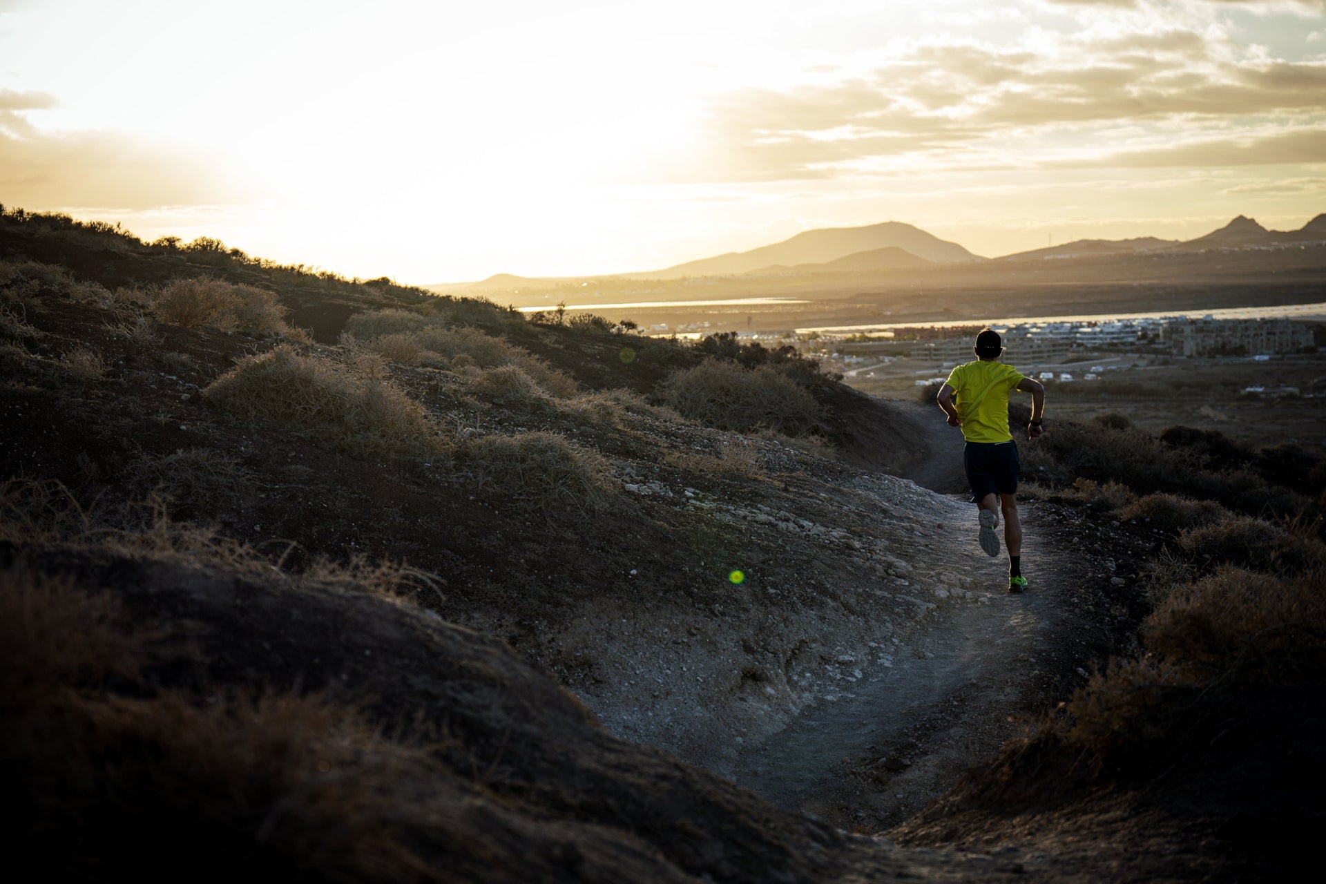 Person running on a trail with mountains in the background