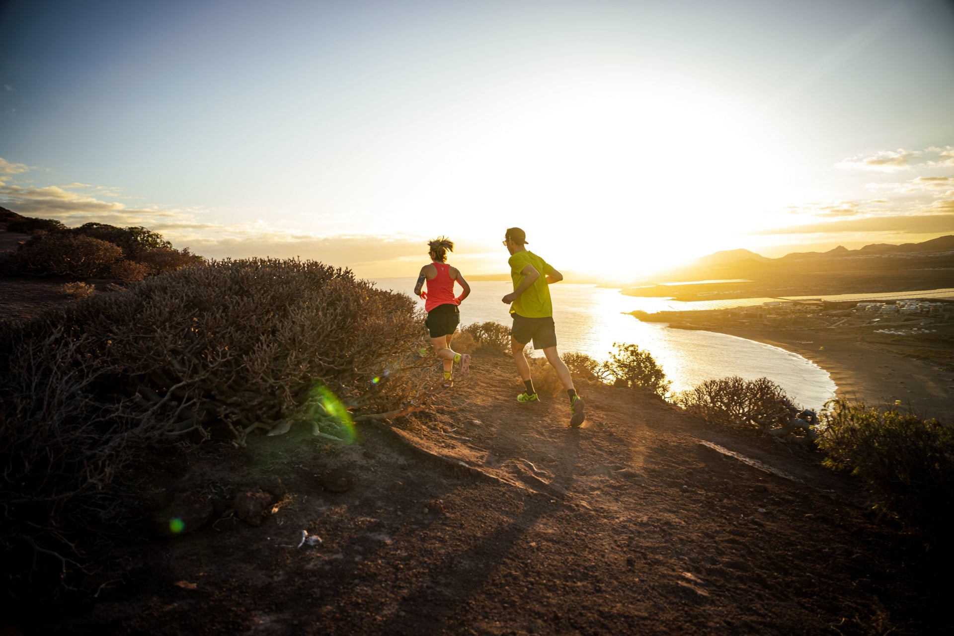 Two people running on a trail with mountains in the background