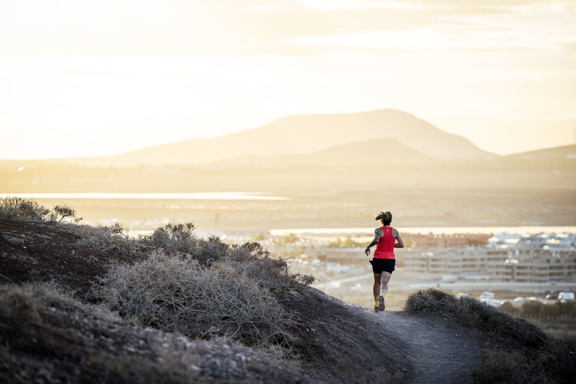 Person running on a trail with mountains in the background