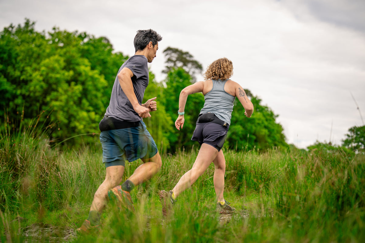 Two people running on a muddy path