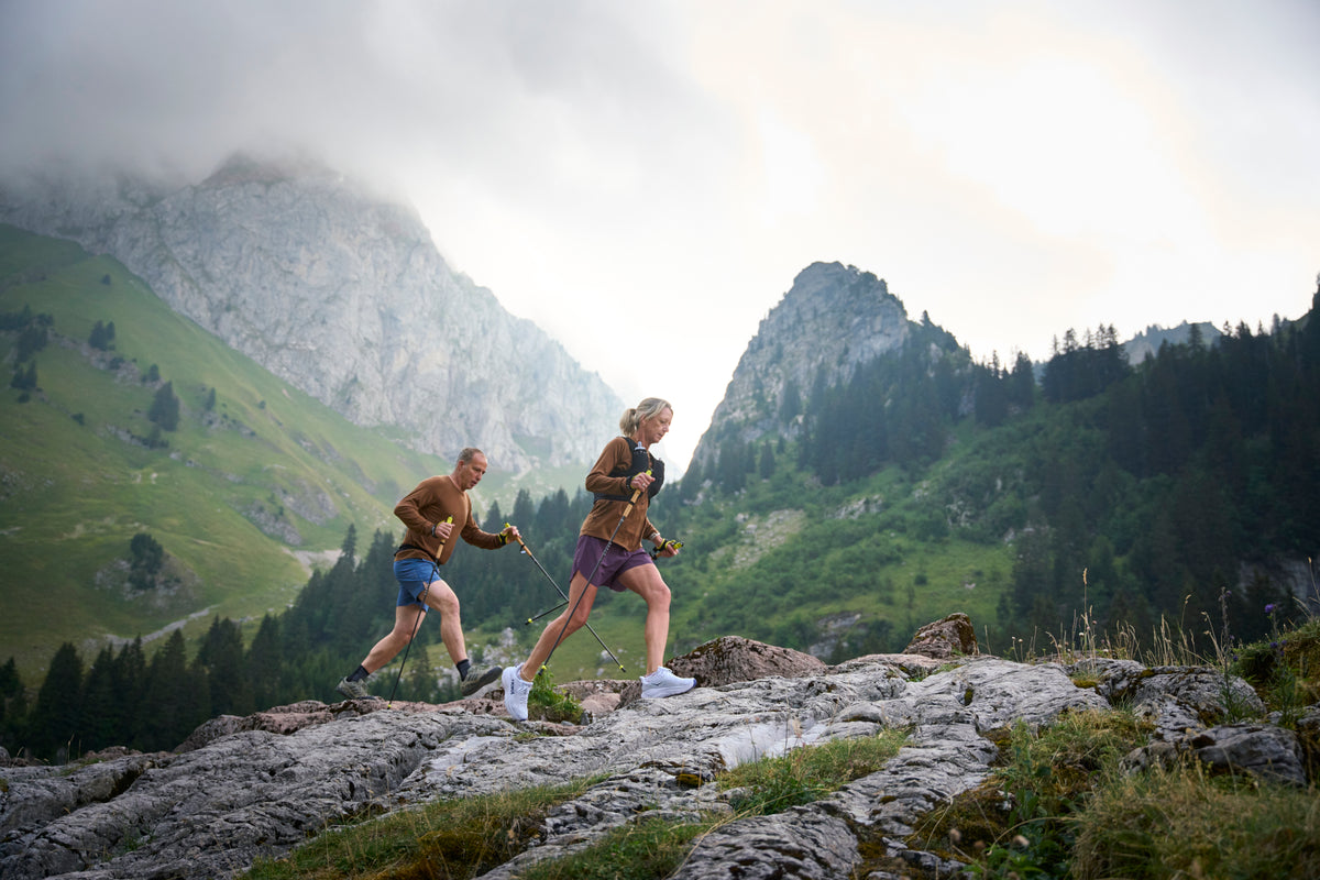 Two runners on a mountain trail with running poles