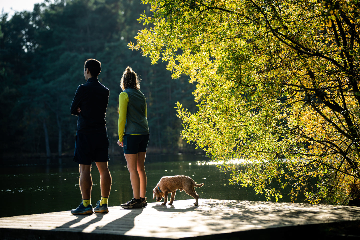 Two runners standing on a deck by a lake