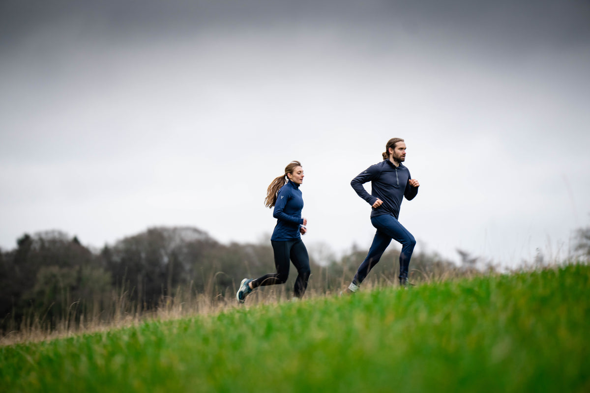 Two people running up a grassy hill