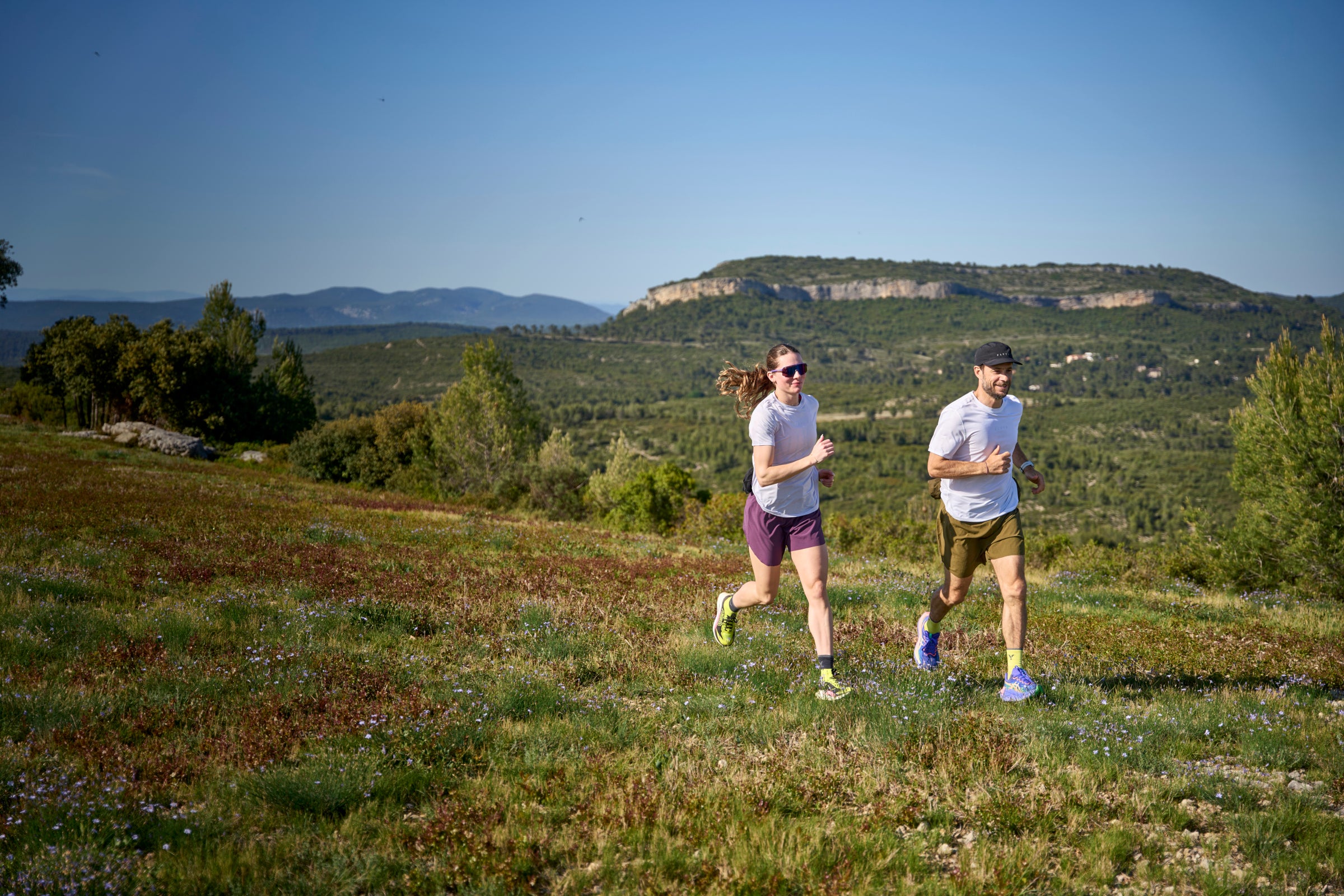 Two people running on a grassy hill