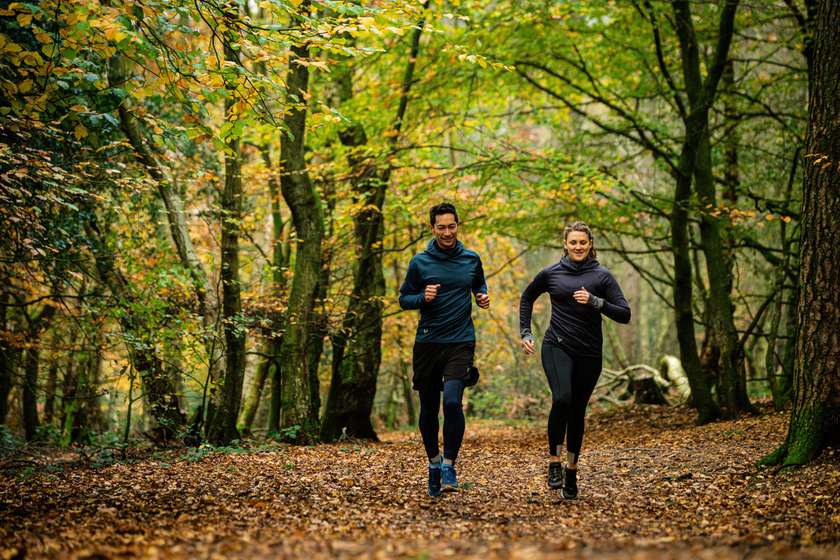 Two people running through a forest