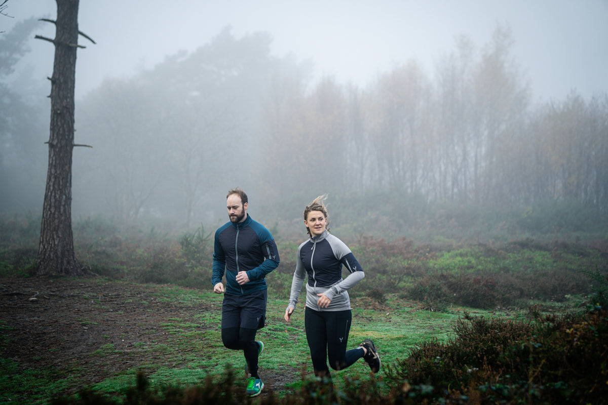 Two people running through a foggy forest