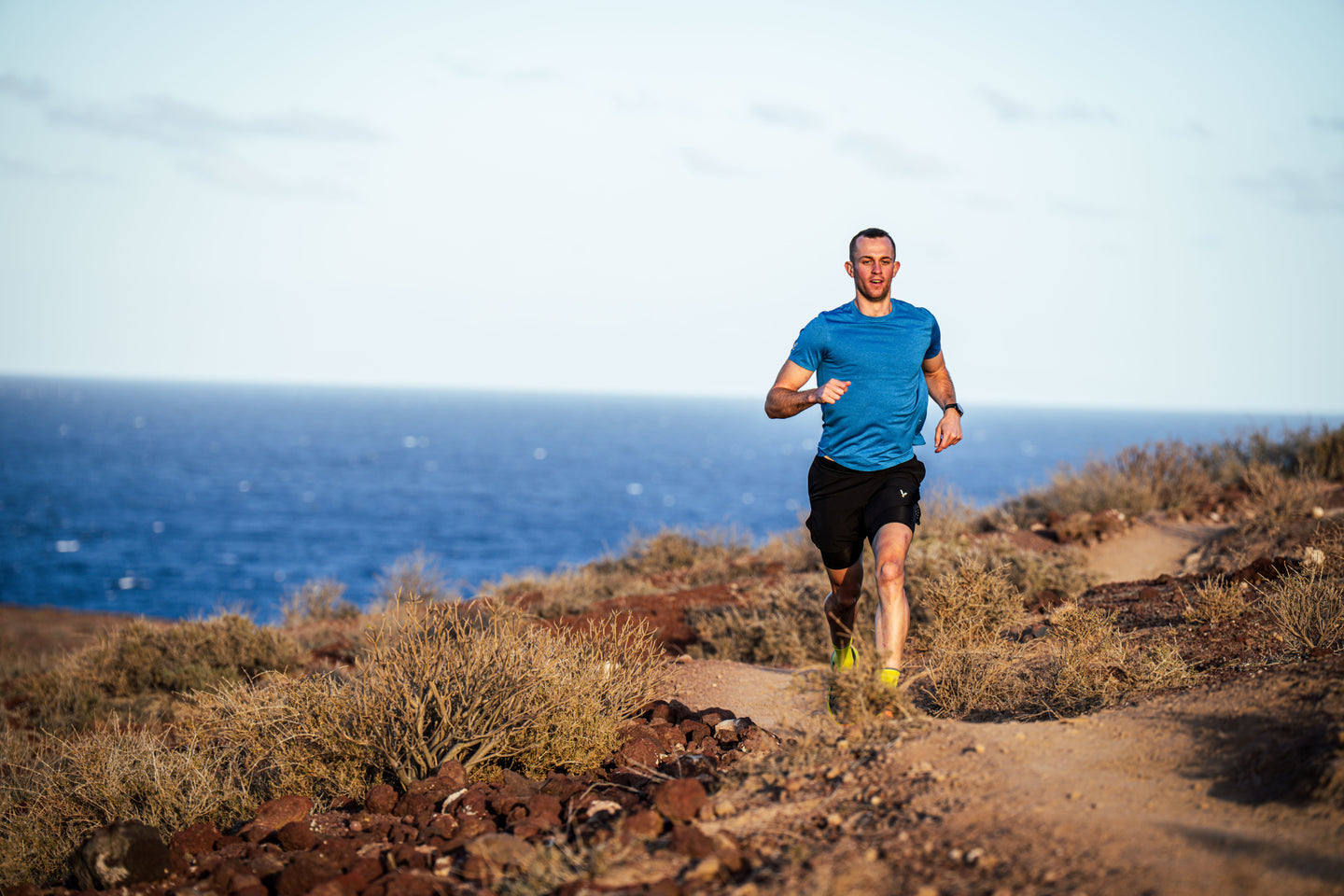Man running on a trail with ocean view