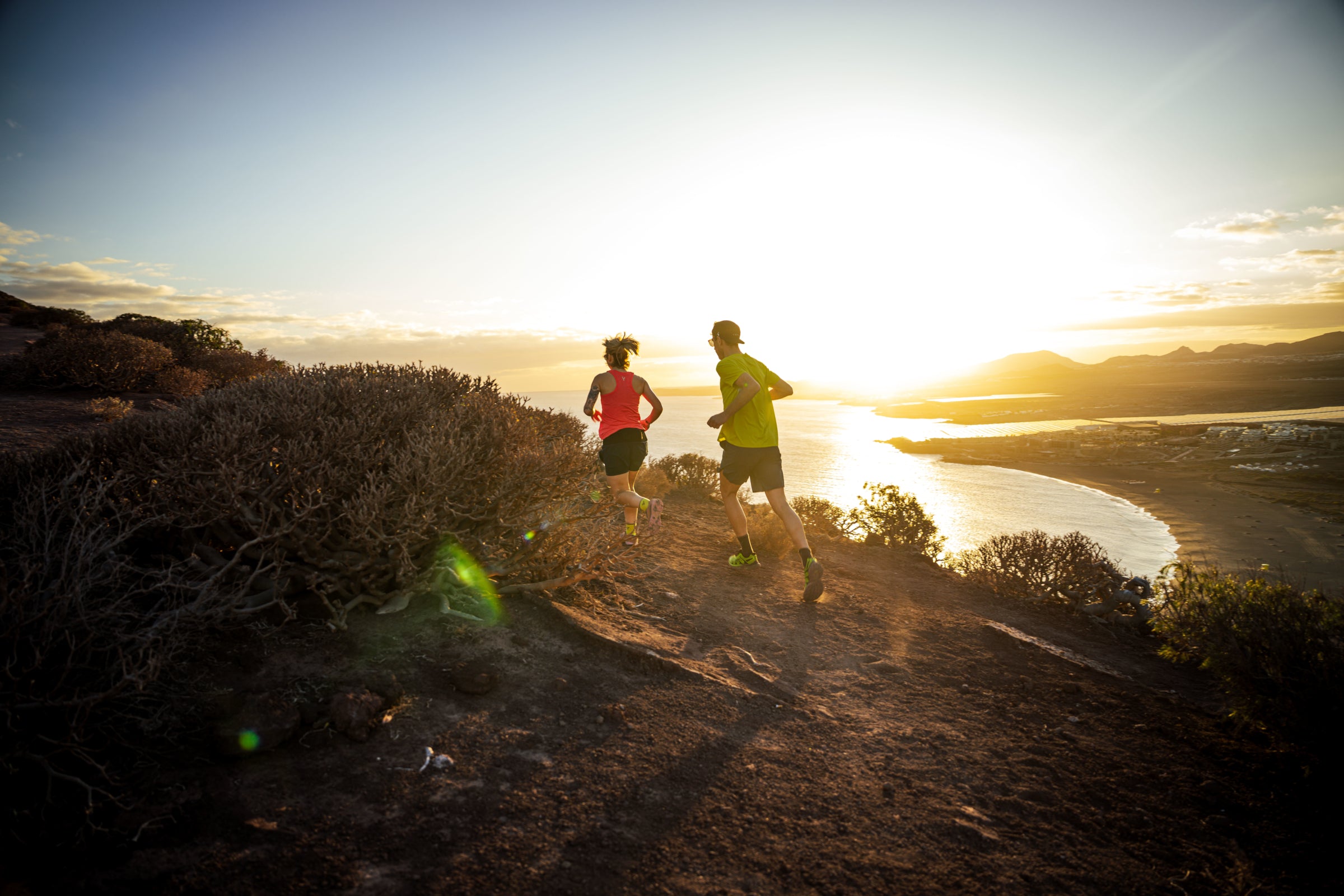 Two people running on a trail with mountains in the background