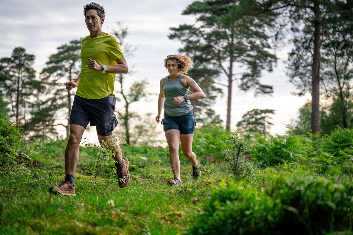 Two people running through a forest