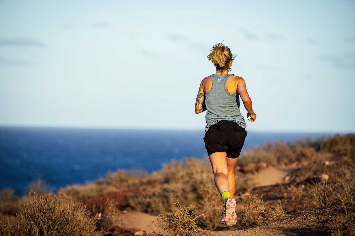 Woman running on a sandy trail by the ocean