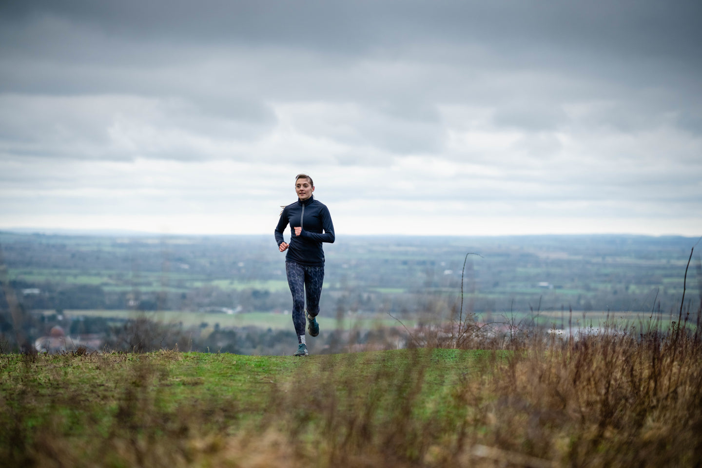 Woman running up a grassy hill