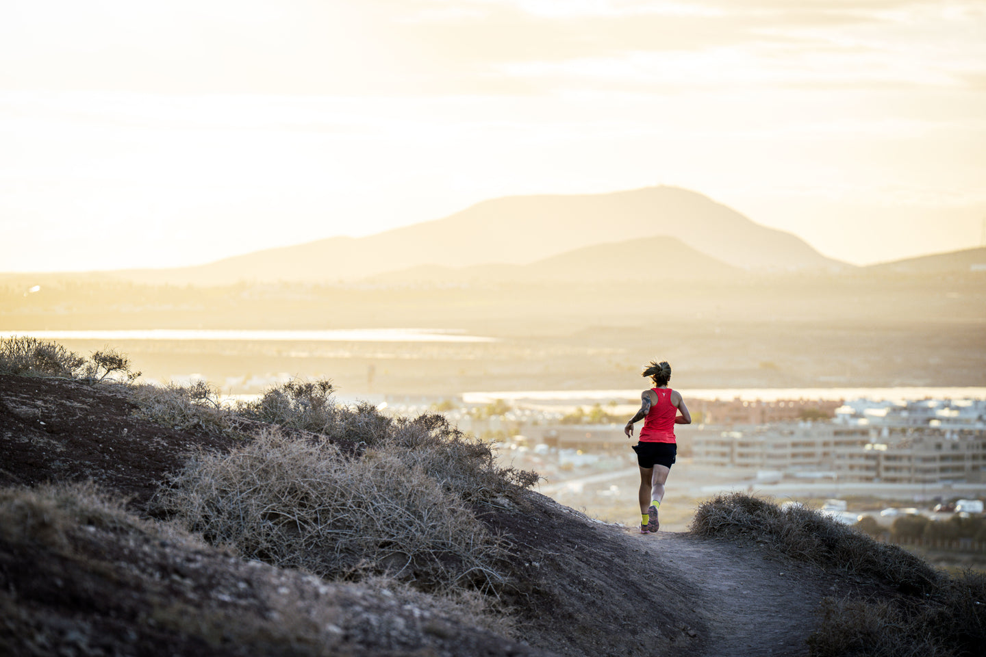 Person running on a trail with mountains in the background