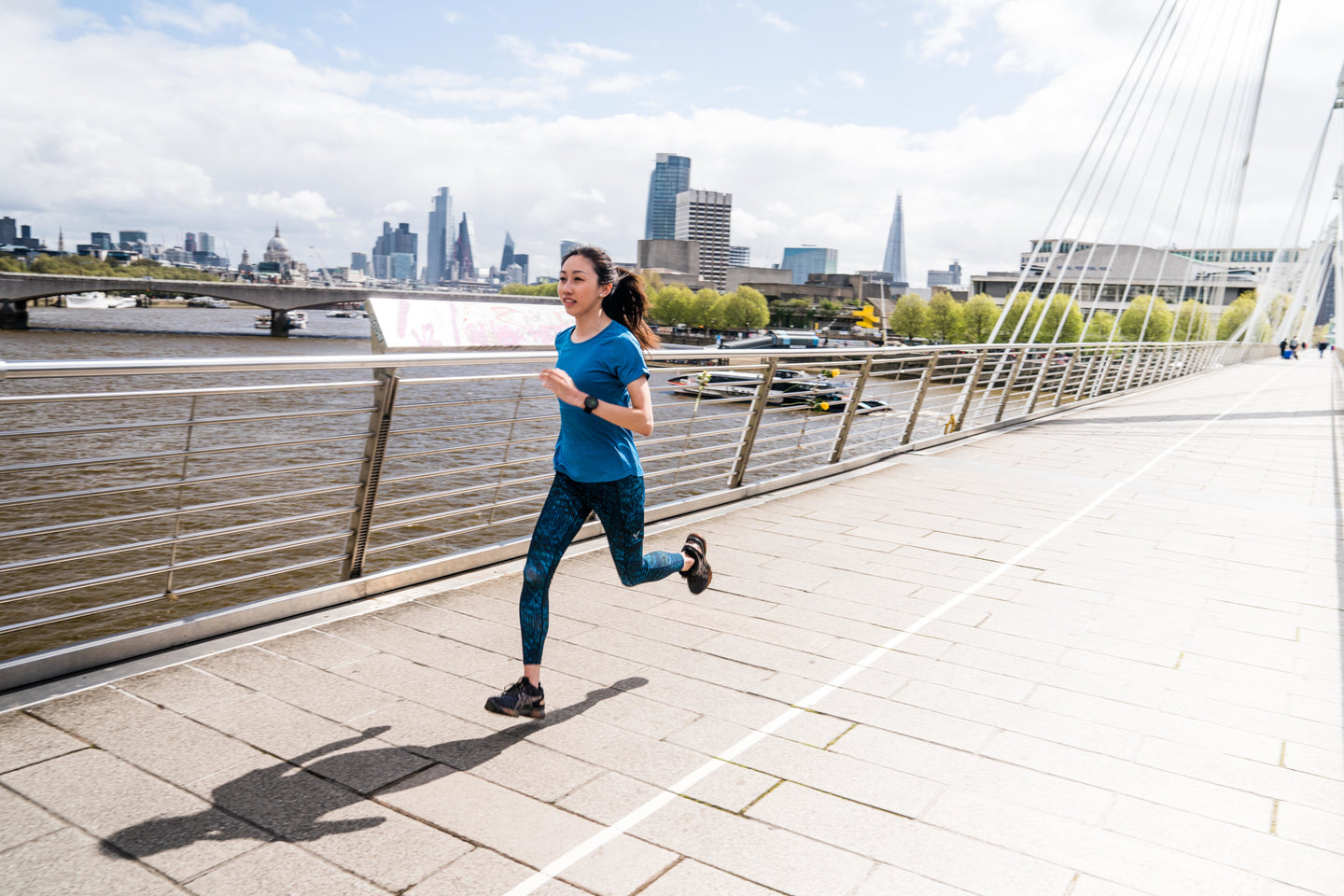 Person running on a bridge with a city skyline in the background