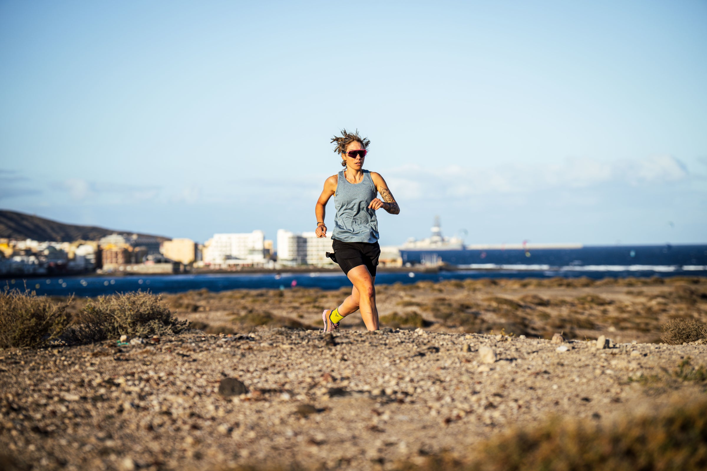 Person running on a beach path with buildings and ocean in the background