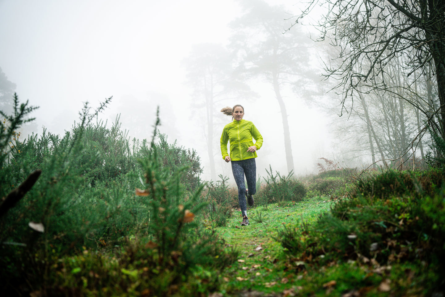 Person running through a foggy forest path
